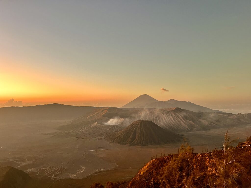 Scenic view of Indonesia featuring lush green rice terraces, a towering volcano in the distance, and vibrant tropical flora, showcasing the natural beauty and cultural richness of Southeast Asia's largest archipelago. Perfect for travel inspiration, adventure tourism, and exploring Indonesia's unique landscapes; Best Volcanoes to Visit in Indonesia