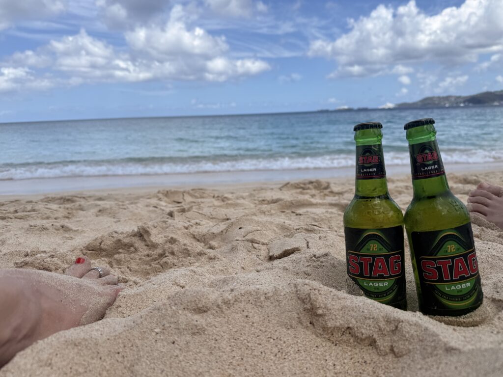 Wide white sand beach at Grand Anse, Grenada, with calm turquoise Caribbean Sea and lush green hills in the background; Best beaches in Grenada