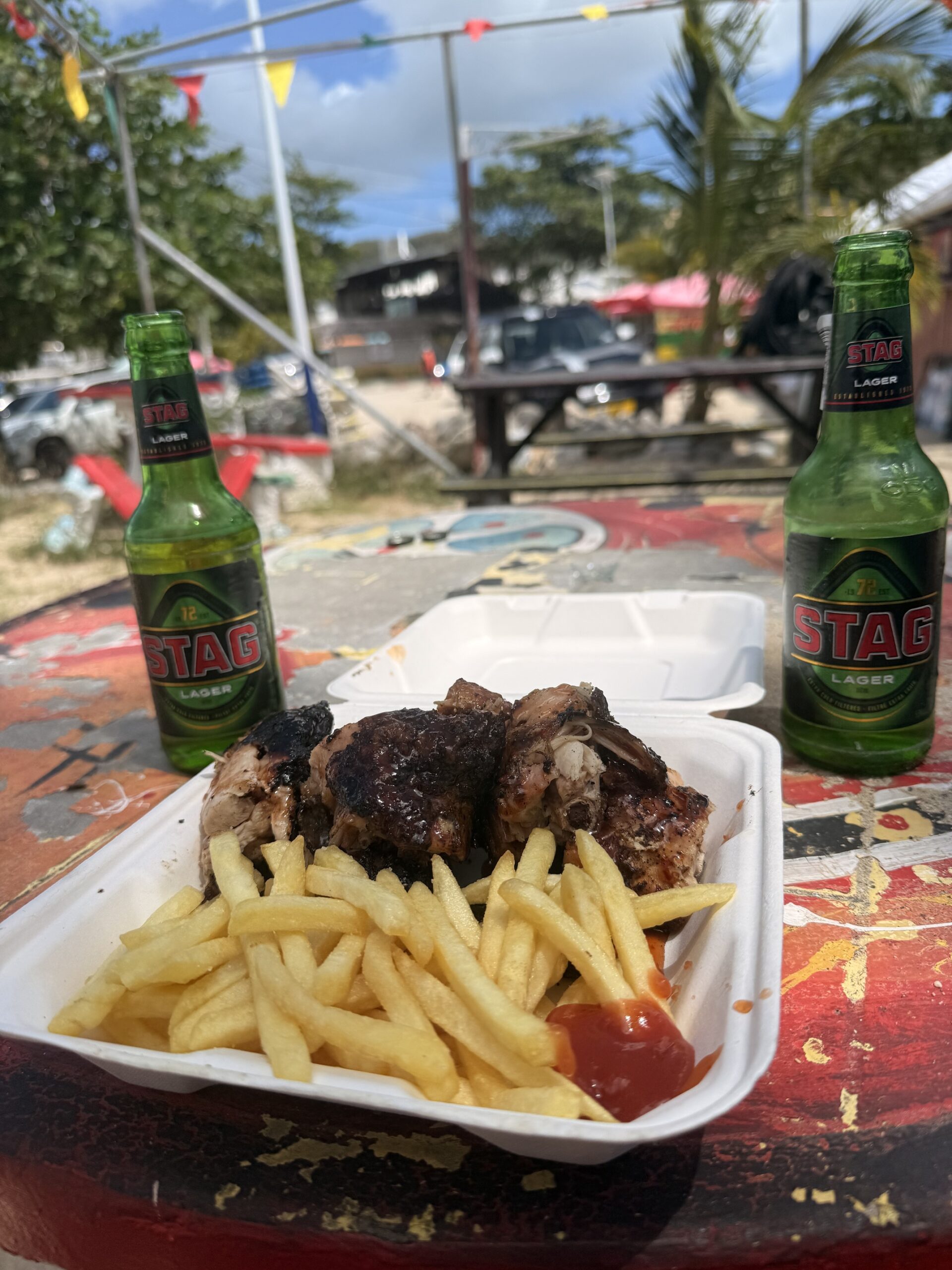 Wide white sand beach at Grand Anse, Grenada, with calm turquoise Caribbean Sea and lush green hills in the background; Grenadian food to try