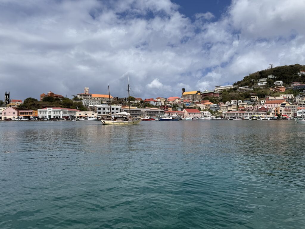 colourful colonial buildings lining the waterfront of St. George's harbour, Grenada, with fishing boats moored in the calm blue Carenage