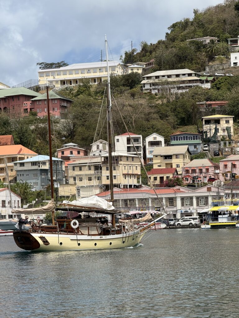 colourful colonial buildings lining the waterfront of St. George's harbour, Grenada, with fishing boats moored in the calm blue Carenage